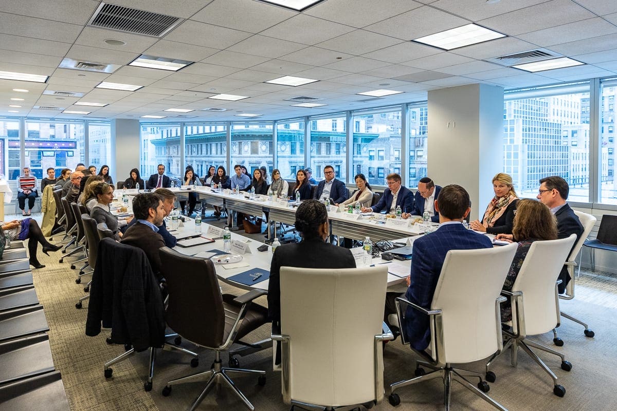 Men and women sit at a conference table discussing environmental, social and governance, or ESG, frameworks at an MFA forum.